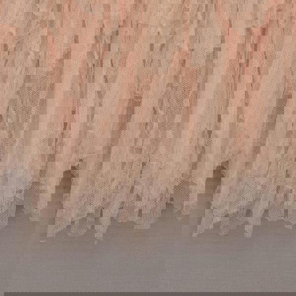 Close-up of a layered tulle skirt in a soft apricot color on a neutral background.