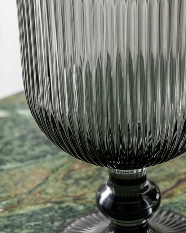 Set of ribbed glass goblets on a wooden surface with a pine cone.