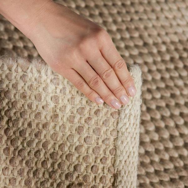 Hand touching a textured beige cushion against a matching background