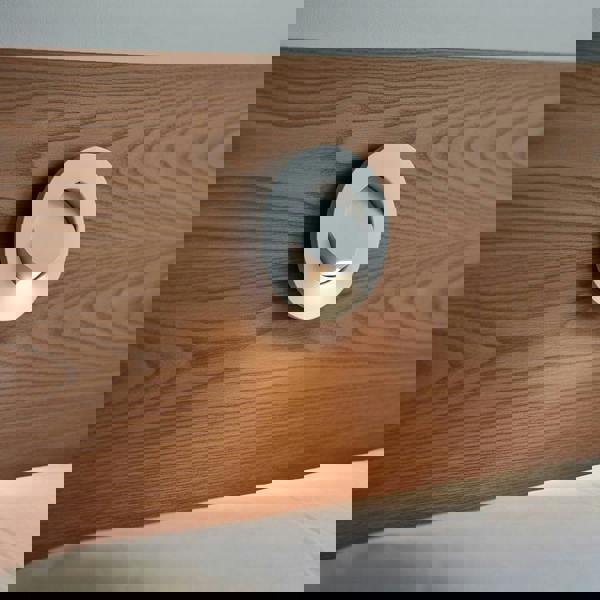 White recessed bedside reading light mounted into a wooden headboard above a bed