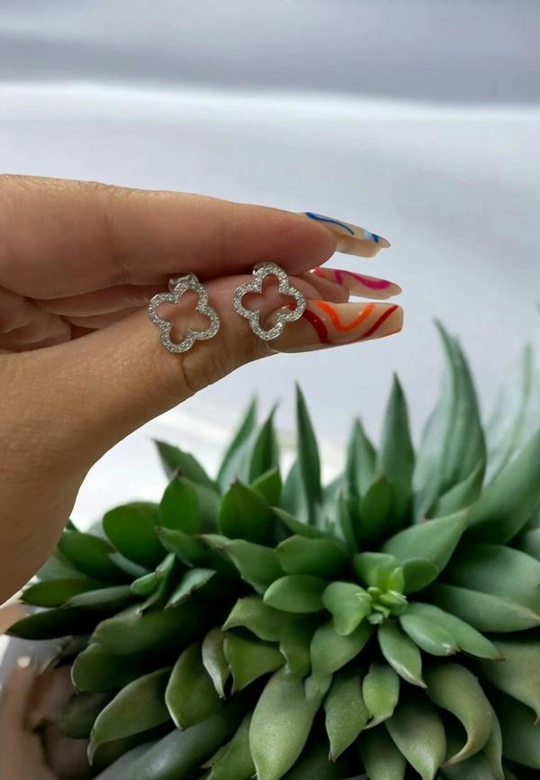 The earrings held up by a hand model.