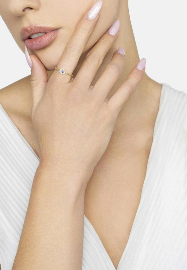 Close-up of a hand wearing a ring with a blue gemstone, against a neutral background.