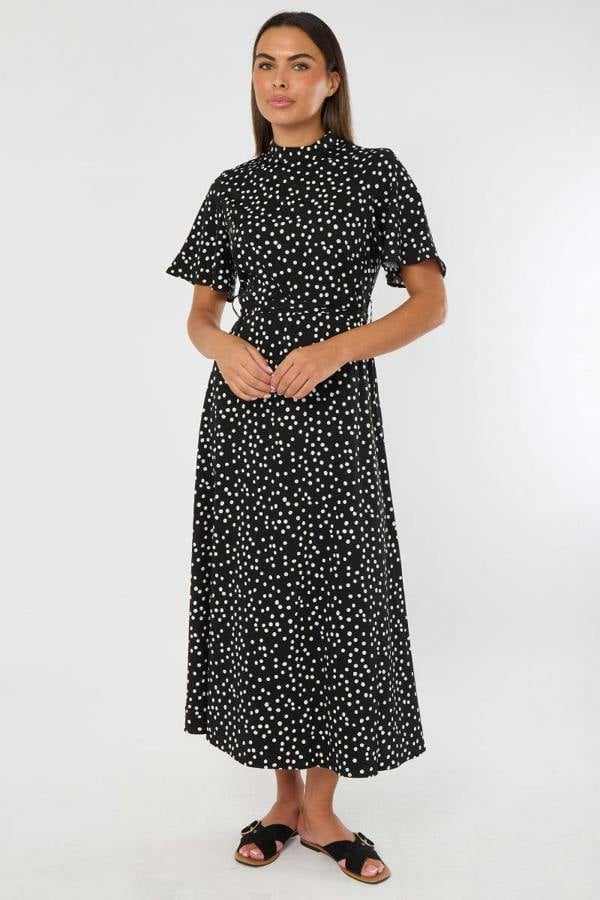 Woman wearing a black dress with white polka dots on a white background