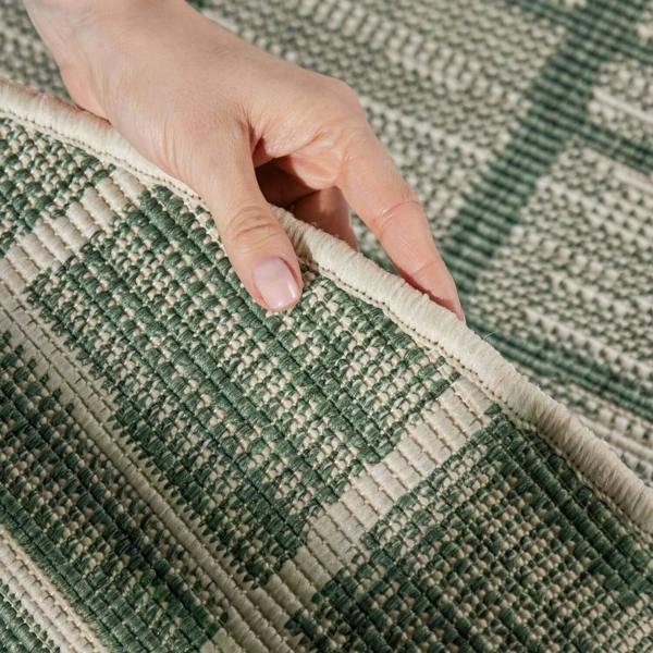 Hand touching a green and beige checkered patterned rug