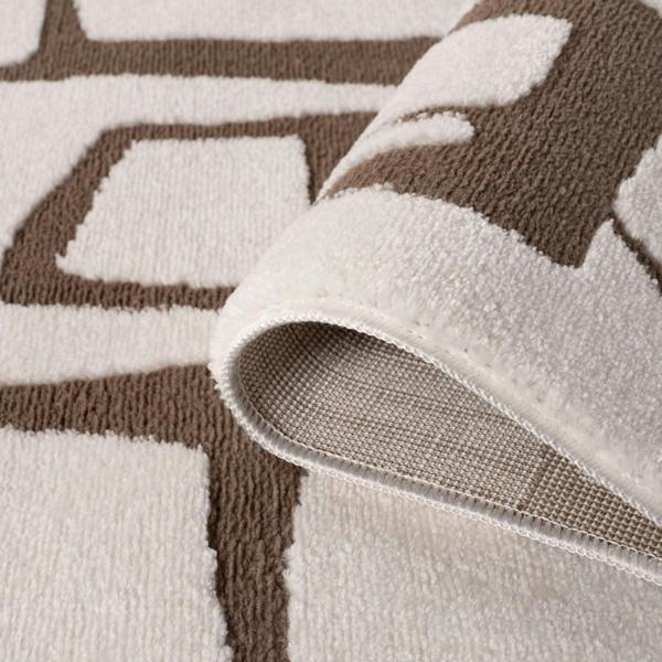 Close-up of a brown and beige patterned rug with a rolled edge.