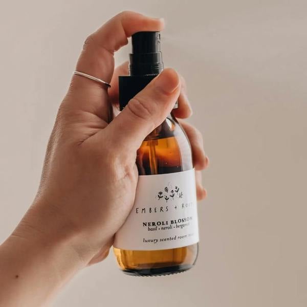 Hand holding an amber glass bottle of luxury room spray mist with black spray nozzle