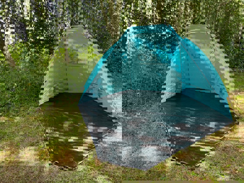 An image of the Blue Beach Tent from OLPRO pictured in front of a tree line.