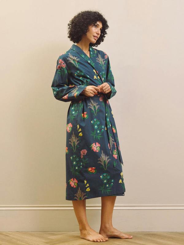 Woman wearing a navy blue floral patterned robe against a beige wall.