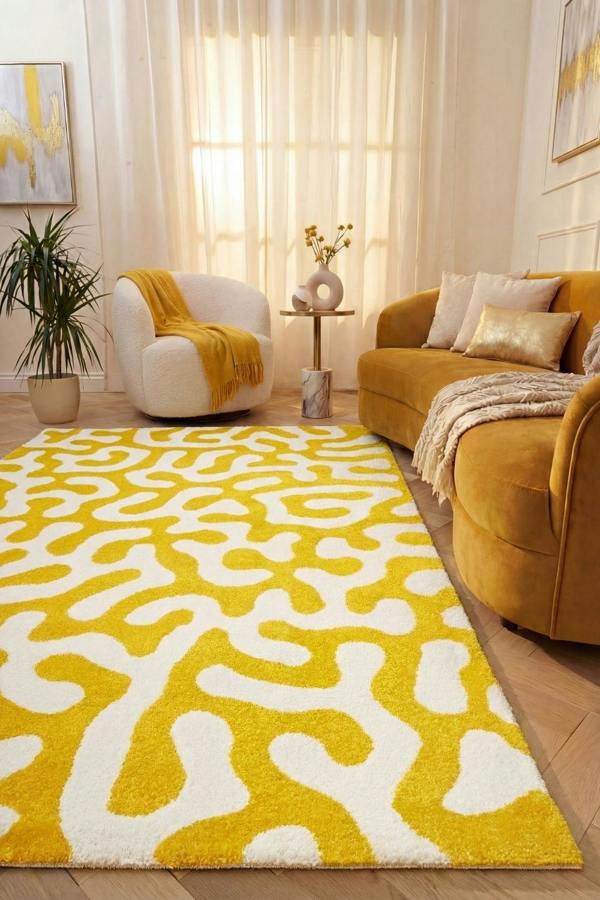 Living room with a yellow and white patterned rug, mustard-colored sofa, and white armchair.