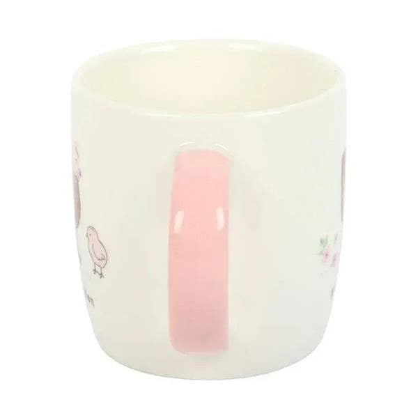 White ceramic mug with pink interior thumb grip panel and small hen-and-floral prints.