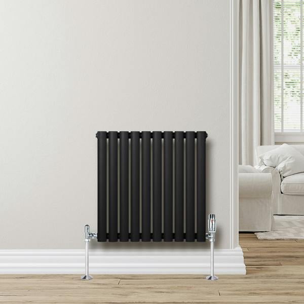Sleek black oval single column radiator, 600 x 600mm, mounted on a wall with chrome valves, enhancing modern interior decor
