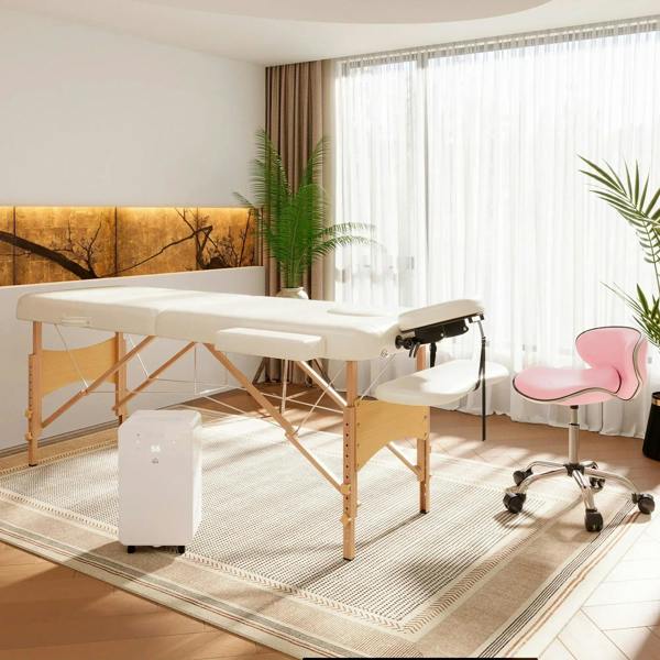 Cream portable massage table with face cradle and wooden frame, plus padded side stool