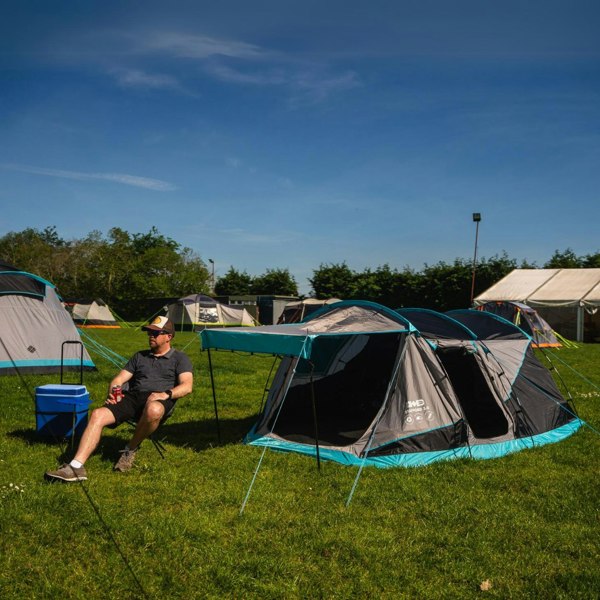 A man sits in an olpro camping chair by a Stafford 3.0 tent