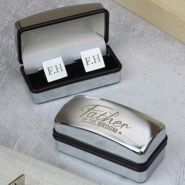 A pair of silver square cufflinks engraved with the initials 'D.M.' resting inside an open, reflective silver chrome presentation gift box against a clean dark grey background.