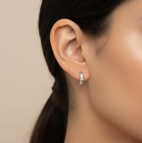 BLOOMTINE_STERLING_SILVER_MOISSANITE_HOOPS_THE_PERFECT_GIFT_FOR_HER. Close-up of an ear wearing a silver hoop earring with a neutral background