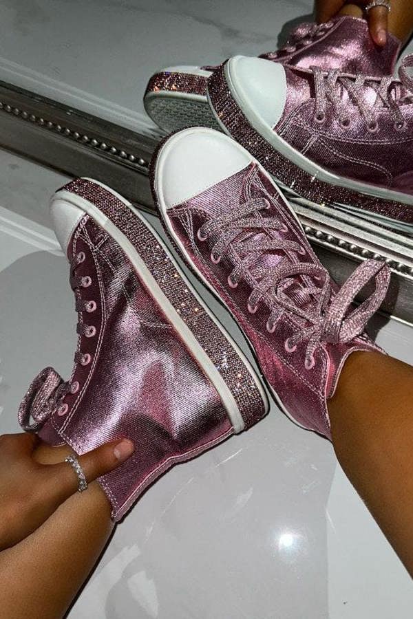 Pink glittery high-top sneakers being worn with a reflective surface in the background