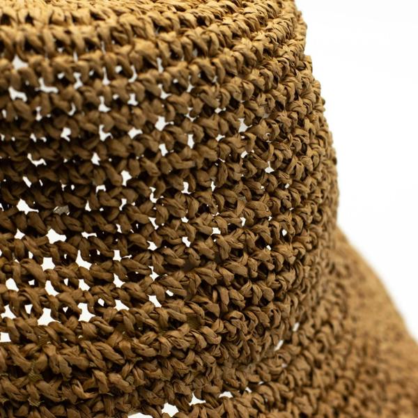 Close-up of tan woven straw texture on floppy sun hat brim