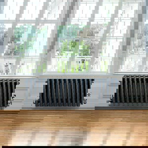 Traditional anthracite 4 column radiator, 300 x 1010mm, featuring a sleek design, installed beneath a large window in a bright room