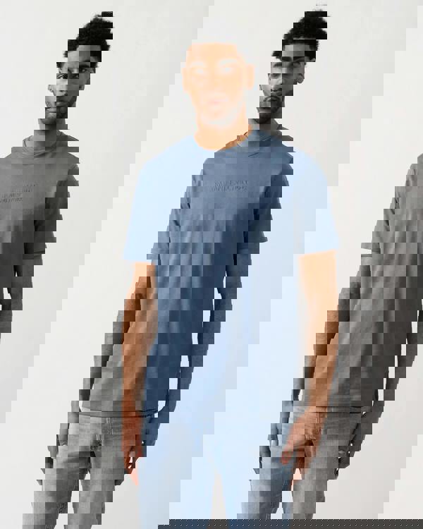 Model wearing an Armani Exchange Mens T-Shirt with Tonal Milano/New York Logo in China Blue U9302