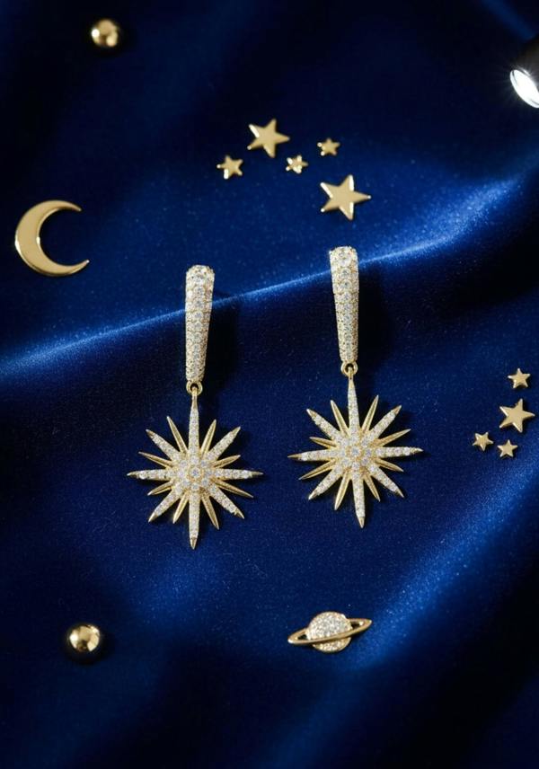 Gold star-shaped earrings on a blue satin background with celestial decorations.