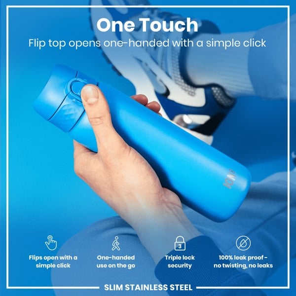 A blue, slim stainless steel water bottle is being held; its flip top opens one-handed via a simple click; it's shown against a blue background with a blurred-out person's lower body and shoes.