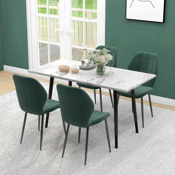 Emerald green upholstered dining chairs with quilted backs and dark metal legs around table