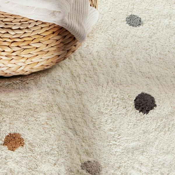 Close-up of a textured beige carpet with dark spots and a woven basket.