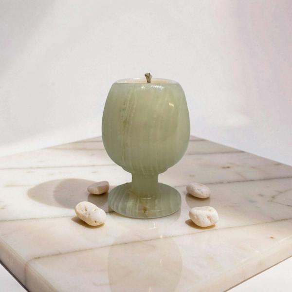 Green ceramic goblet on a wooden surface with small stones around it