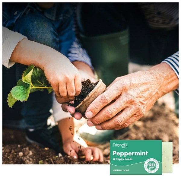 Child and senior hands working together to pot a plant in the garden