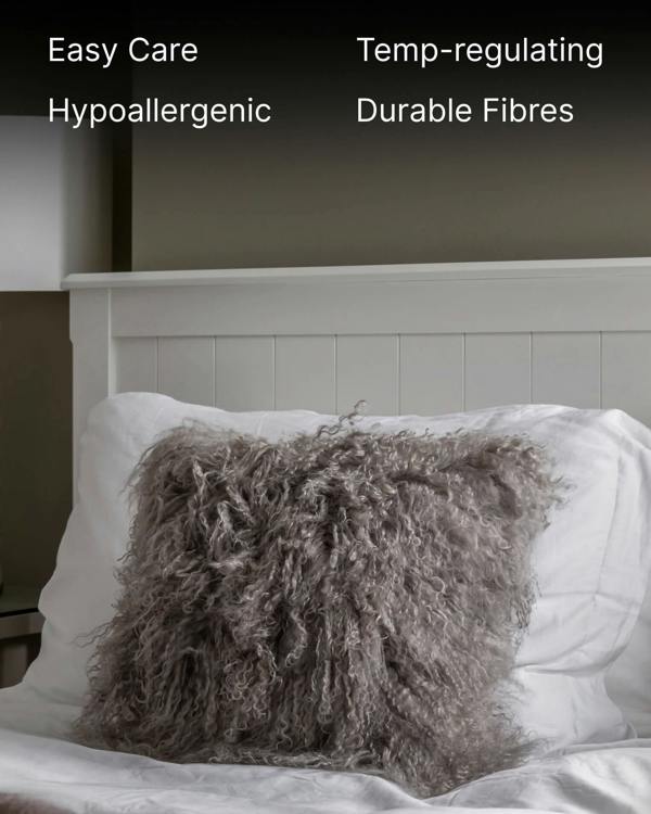 Grey mongolian sheepskin pillow on white bed