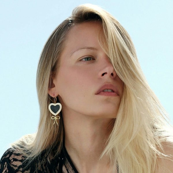 A blonde model wearing black and white heart earrings.