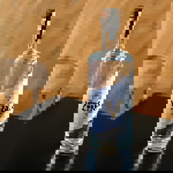 Bottle of Silver Circle Vodka on a dark surface with a blurred wooden background

