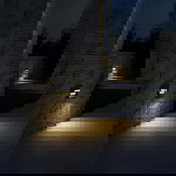 black low level wall light mounted on a stone wall outside of a modern home