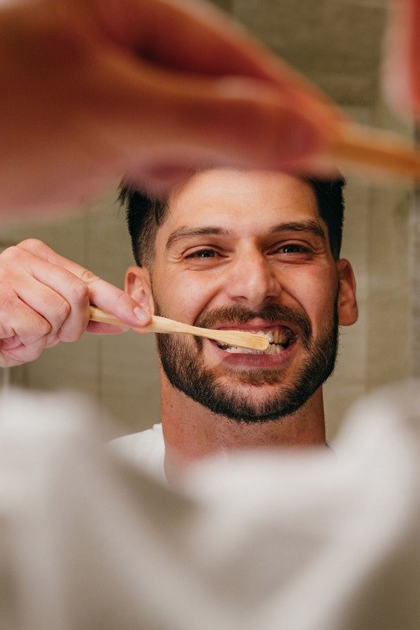 smiling man brushing teeth with bamboo toothbrush