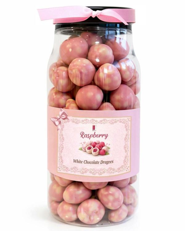Jar of raspberry white chocolate dragees with a pink lid on a white background