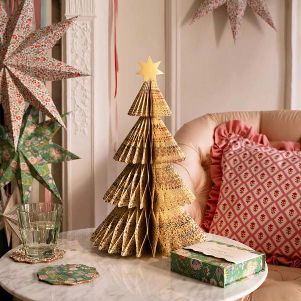 A 3D paper honeycomb Christmas tree with an intricate gold-toned Liberty floral print pattern and a metallic gold star on top, sitting on a marble table.