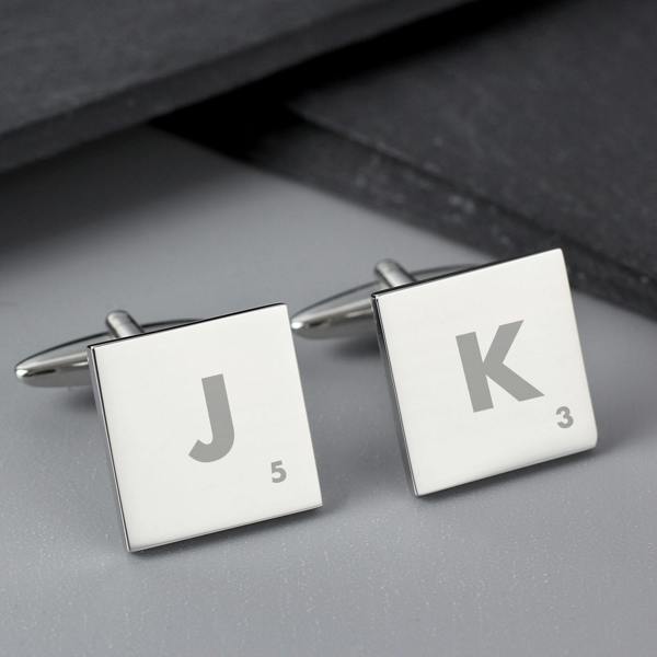Two square personalised cufflinks with T and G initials positioned on a textured slate surface.