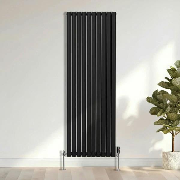 Sleek black oval column radiator with vertical bars, measuring 1800mm x 600mm, mounted on the wall beside a potted plant