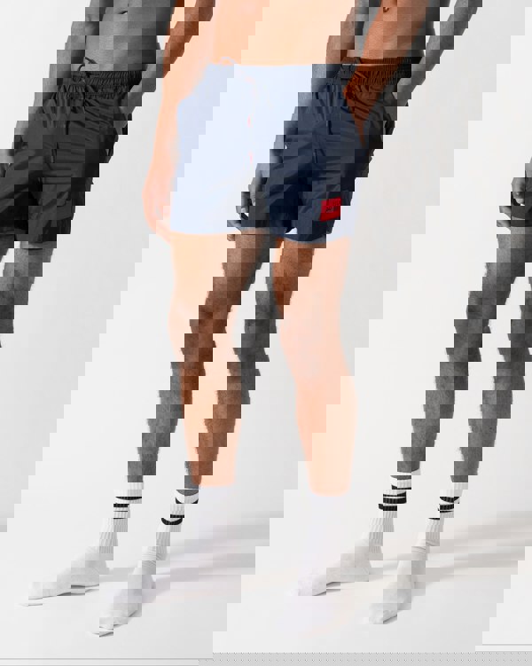 Model wearing a HUGO Dominica Mens Quick-Drying Swim Shorts In Recycled Material With Logo in Dark Blue