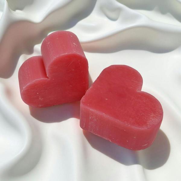 Two red heart-shaped objects on a white textured surface