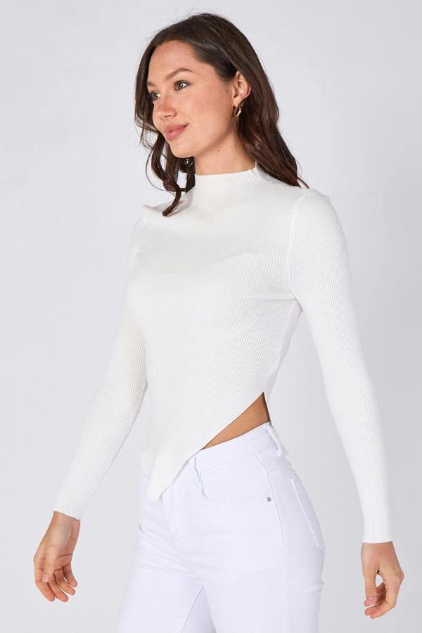 Woman wearing a white long-sleeve top and white pants on a light gray background