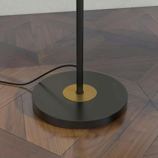Grey circular base of a standing floor lamp with central pole on wooden floor