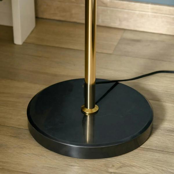 Round black base of gold tone floor lamp with visible pole base connection and cord