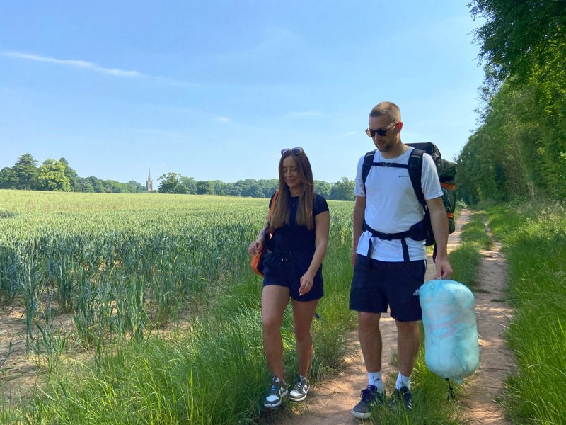 A young couple out walking with a rucksack and carrying an Insulated Outdoor Blanko. imageset:Tonal Tree Tops