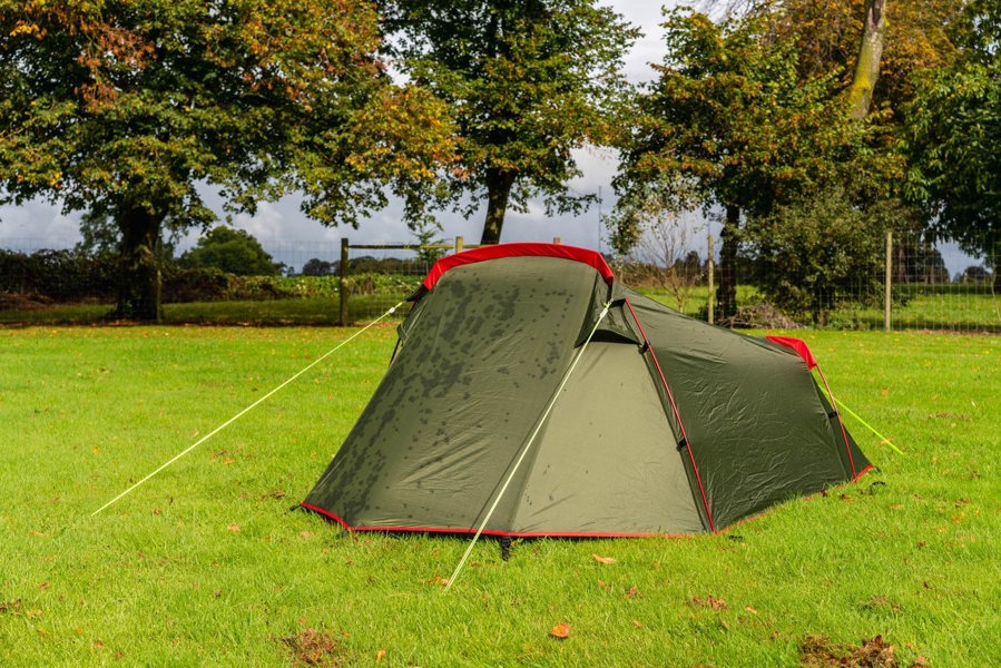 The OLPRO Beckford Lightweight 2 Person Tent pitched on a campsite against a tree line