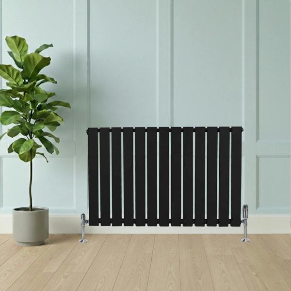 Flat black single column radiator, 600 x 910mm, with vertical slats, positioned next to a potted plant on a wooden floor