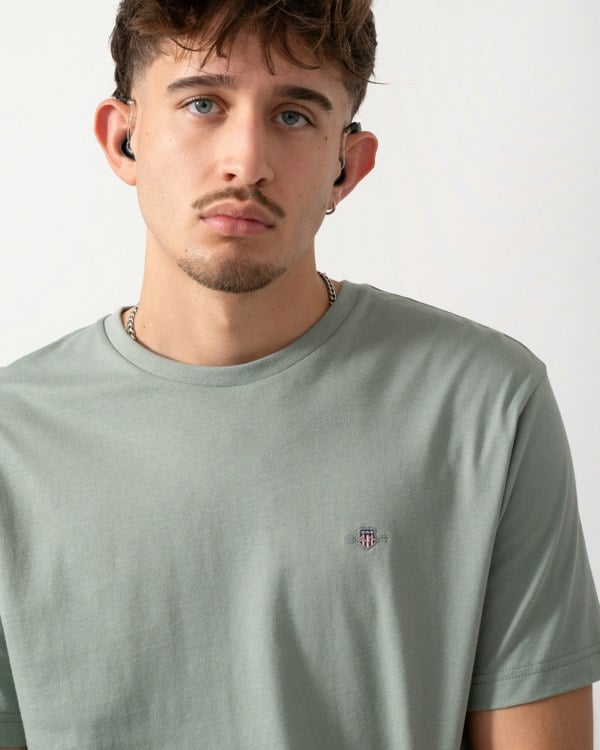 Close up shot of a Model wearing a GANT Mens Regular Fit Short Sleeve Shield Logo T-Shirt in Ceramic Grey