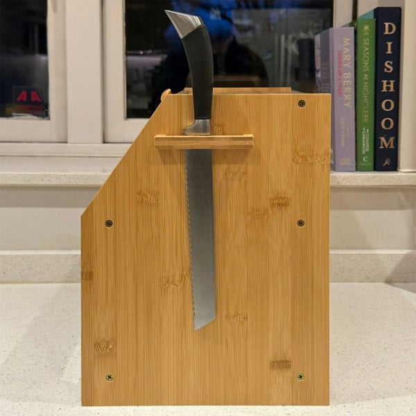 Side view of the bread box showing a bread knife stored vertically in a built-in knife slot on the side panel. The knife holder is integrated into the bamboo wood construction.