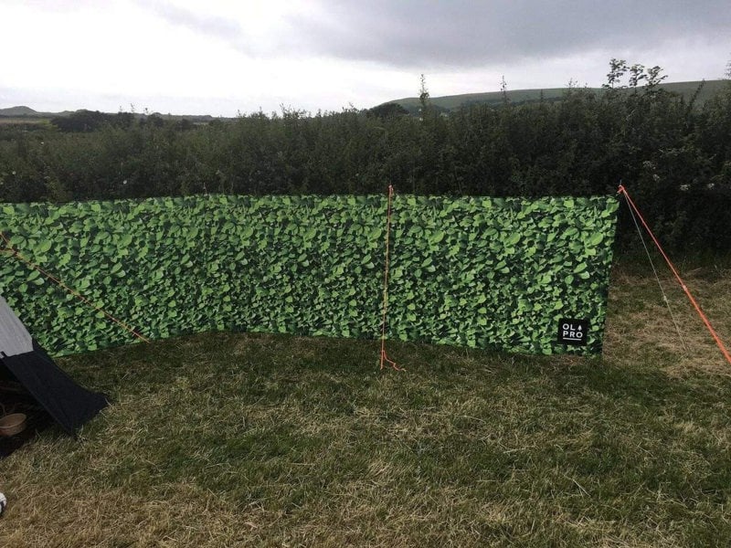 Laurel Hedge 4 Pole Compact Windbreak with Steel Poles by OLPRO pictured in a field next to a tent.