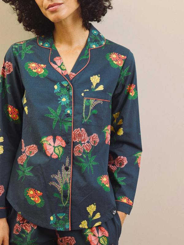 Woman wearing a navy blue floral pyjama set against a plain background